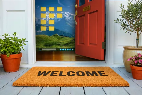 The front door of a building showing a welcome mat. Behind the open red door it shows a computer home screen with several files on the desktop.